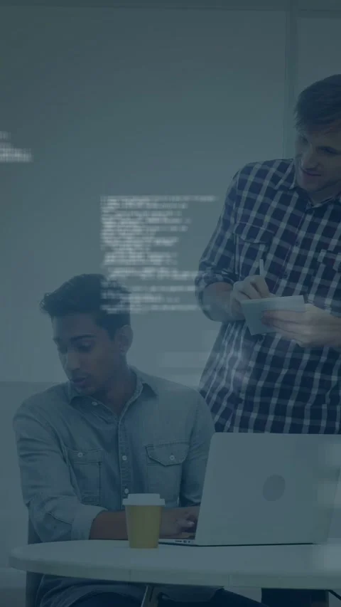 Vertical video: Dev typing at laptop, lead leaning in pointing, driving code Stock Footage 334771146