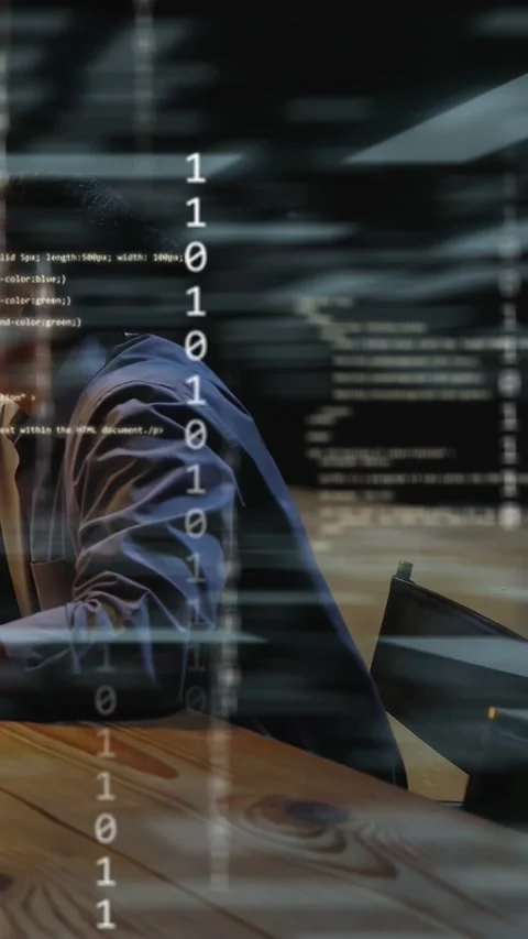 Vertical video: Dev typing at table, causing tech binary overlay while peer Stock Footage 333304178