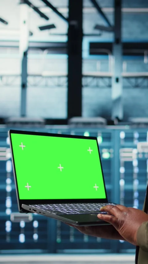 Vertical video Developer in data center using green screen laptop to upgrade Stock Footage 316857368