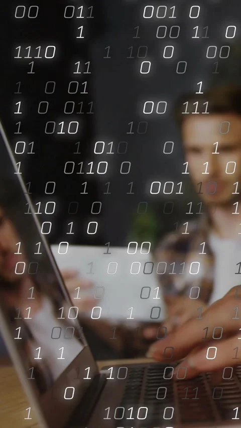 Vertical video: Devs typing on tech laptop, one with white mug, sparking binary Stock Footage 331638800