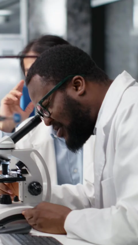 Vertical video Diagnostic laboratory colleagues using microscope Stock Footage 319505172