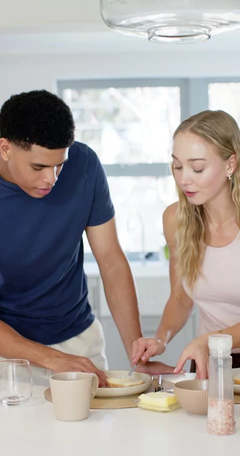 Vertical video: Diverse couple arranging plates in kitchen, spreading food with Stock Footage 345323376
