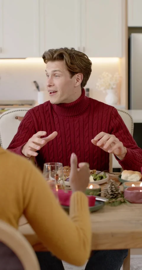Vertical video: Diverse couple dining at kitchen table, man in red smiling, Видео 346735312