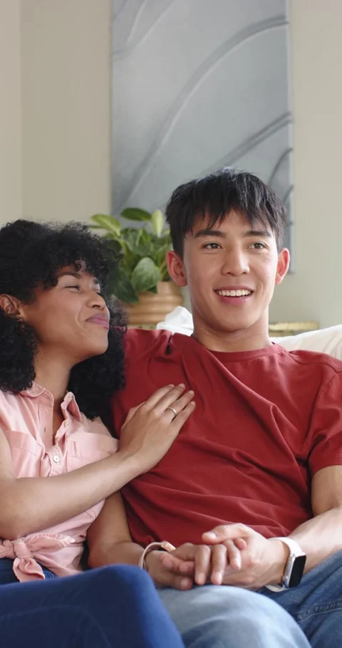 Vertical video: Diverse couple glancing and grinning at screen interlocking Stock Footage 345491964