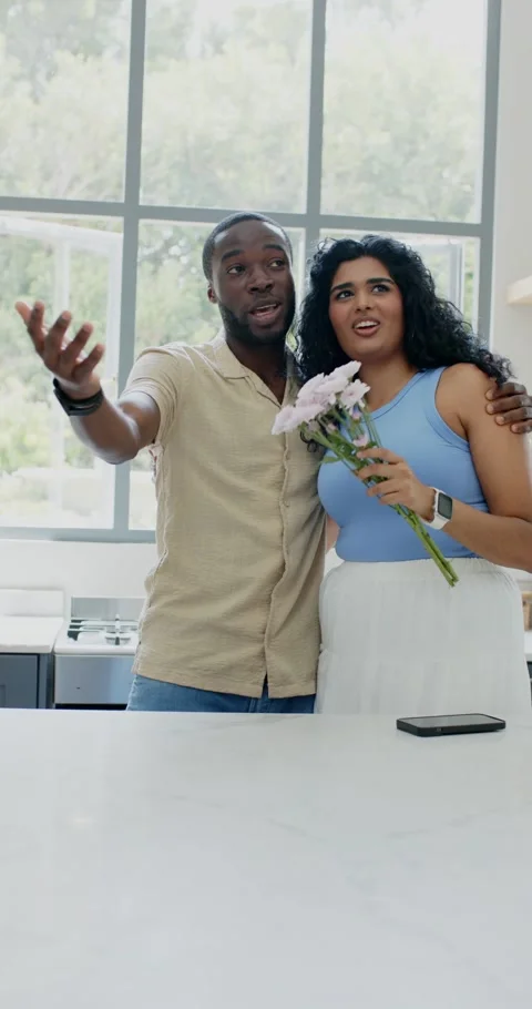 Vertical video: Diverse couple in kitchen man pointing at view woman with Stock Footage 345130222