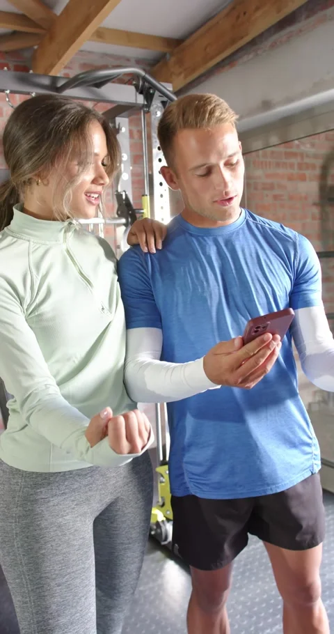 Vertical video: Diverse couple leaning in scrolling phone and checking routine Stock Footage 346724467