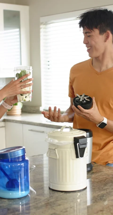 Vertical video: Diverse couple preparing smoothie exchanging jar attaching lid, Stock Footage 345217863