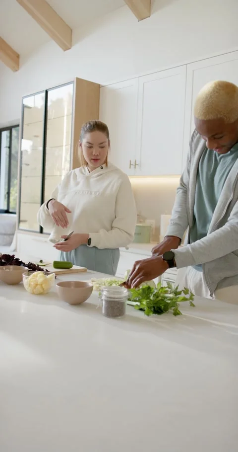 Vertical video: Diverse couple prepping bowls man chopping herbs, woman slicing 스톡 동영상 346735336