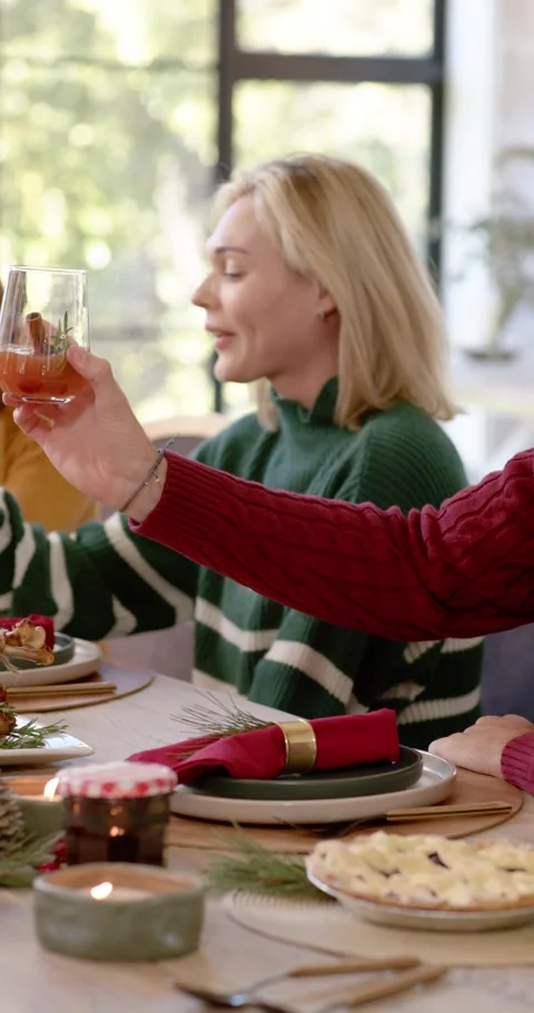 Vertical video: Diverse friends toasting at table, green top woman turning Видео 346735294
