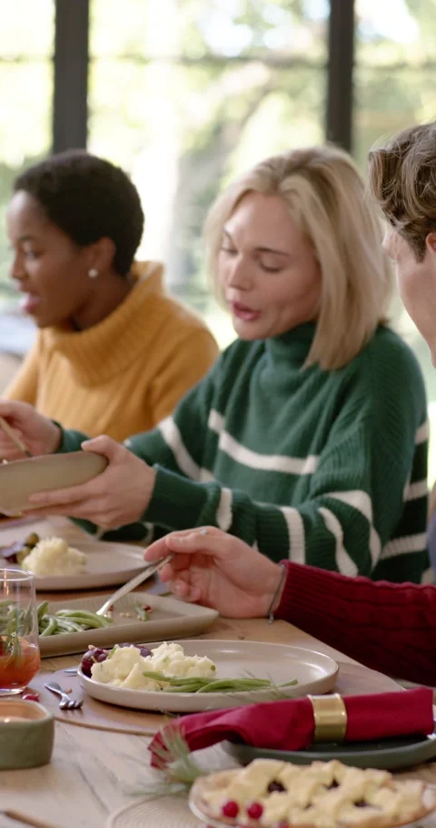 Vertical video: Diverse group dining as striped woman passing bowl, African Видео 346735311