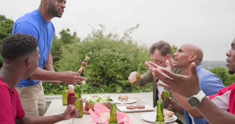 Vertical video: Diverse men seeing host in blue tee carrying kebabs and beer Stock Footage 342494682