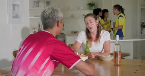Vertical video: Diverse pair sharing chips in kitchen, guest placing beer, Stock Footage 335809379