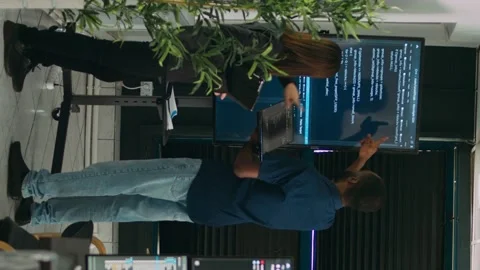 Vertical video: Diverse team of system developers analyzing code on big tv Video stock 219701996