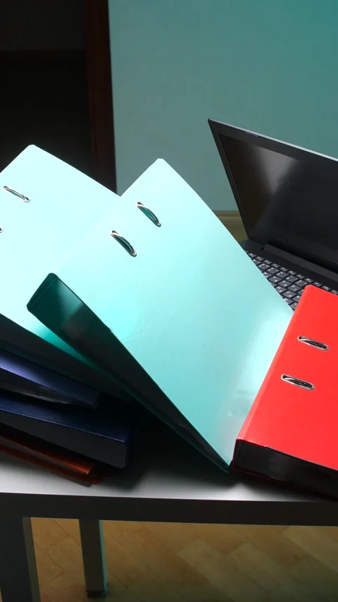 Vertical video documents, folders, and a laptop on a desk representing office Stock Footage 345170081