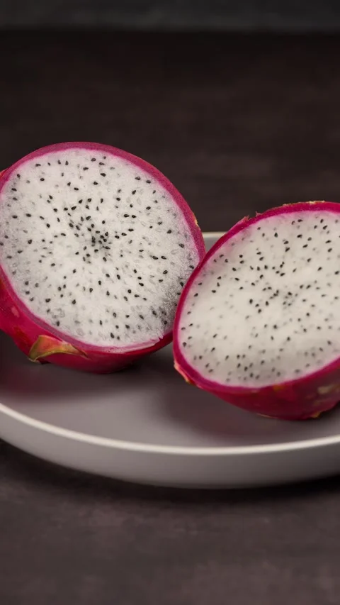 Vertical video, Dragon fruit cut in half showing its interior on a gray plate Stock Footage 281035529