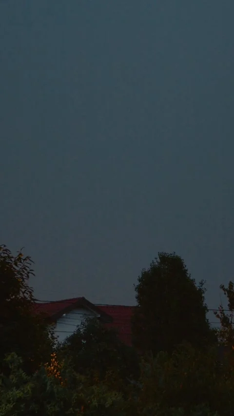 Vertical video Dramatic lightning illuminates the blue sky over a village during Stock Footage 323353213