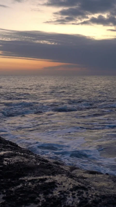 Vertical video of Dramatic ocean waves crashing on rocky coastline at sunset Stock Footage 332228205