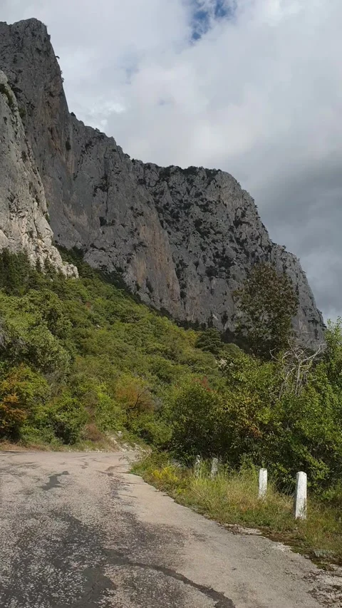 Vertical video. Driving along an old road along a rocky mountain ridge covered Stock Footage 312148299