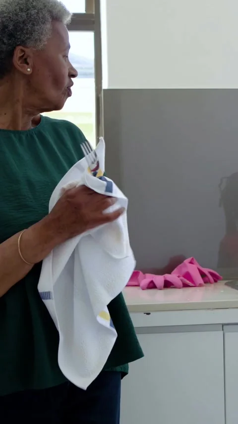 Vertical video: Drying gran in green wiping fork handing it as girl with plates Vídeos de archivo 348821398