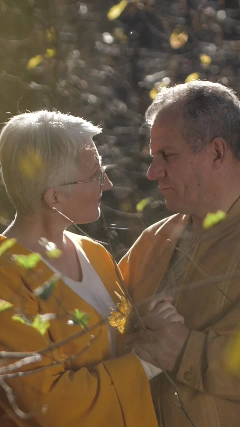 Vertical video. Elderly couple sharing a tender moment in a sunlit forest during Video stock 306843327
