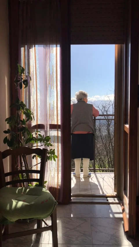 Vertical video- Elderly lady looking out from the balcony. Stock Footage 148565506