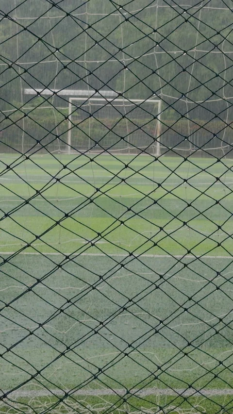 Vertical video. Empty Soccer Field Viewed Through Wet Fence Net During Heavy Rai Stock Footage 320180406