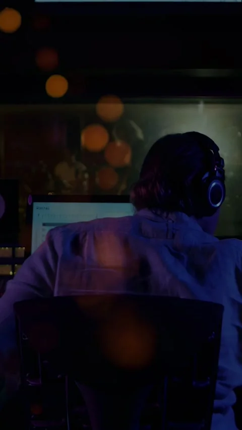 Vertical video: Engineer leaning at console, cueing DAW playback for booth Stock Footage 332547131