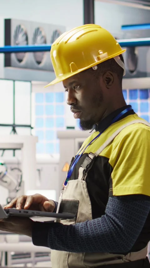 Vertical video Engineer in smart factory does maintenance using laptop software Stock Footage 307145517