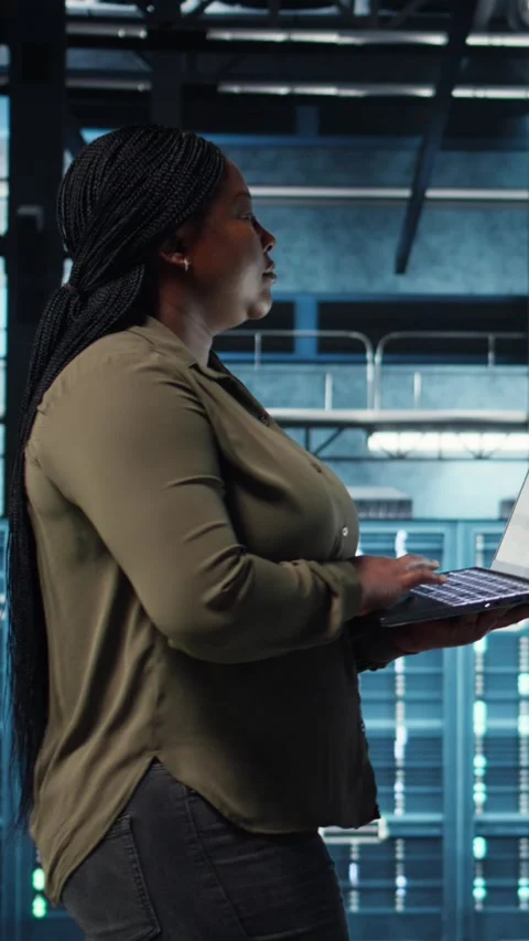 Vertical video Engineer walks in server hub, using laptop to upgrade rigs Stock Footage 317055308