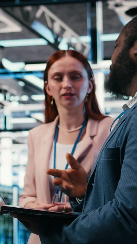 Vertical video Engineering team solving tasks in server farm using laptop Stock Footage 330028524