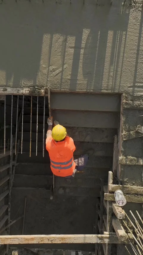 Vertical Video: Expert concrete leveling on a staircase as a worker creates a Stock Footage 297655118