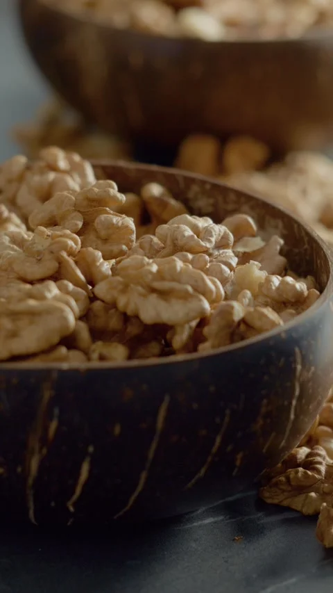 Vertical video Explore walnut kernels in a wooden bowl and on a table for Stock Footage 329617783