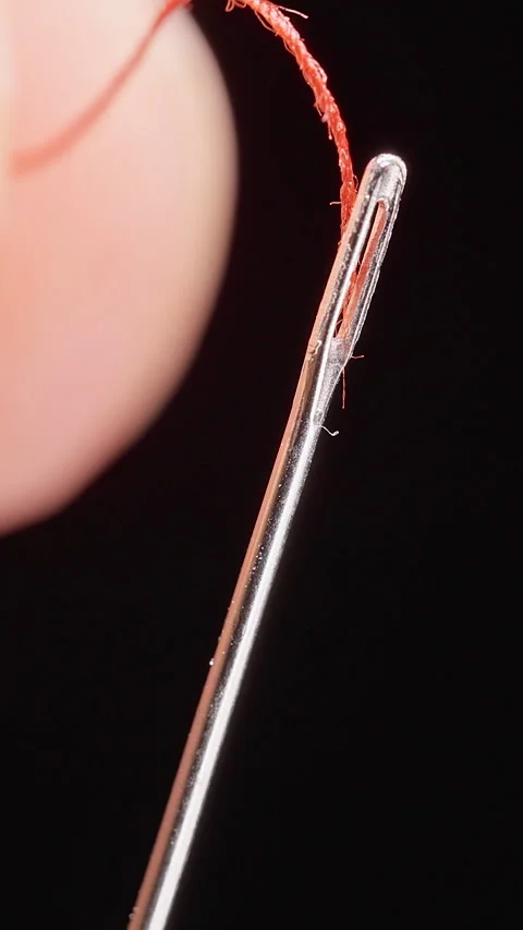 Vertical video. Extreme Macro View of Fingers Failing to Insert Red Thread throu Stockbeeldmateriaal 341415947