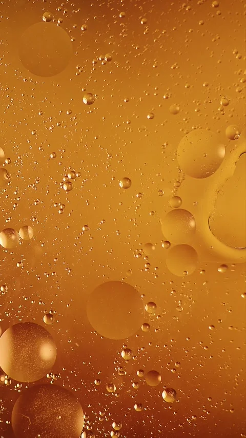 Vertical video of falling drops creating soft waves on orange oil surface Stock Footage 341825065