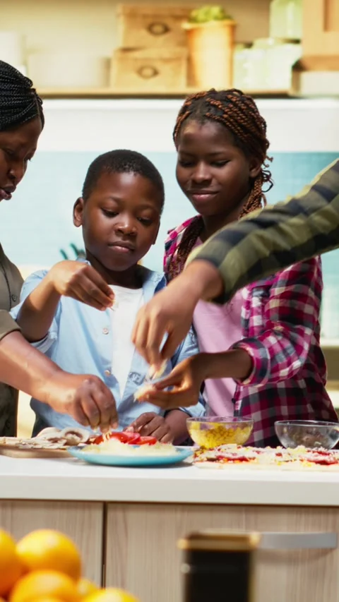 Vertical Video Family fun in the kitchen as everyone is layering cheese and Stock Footage 319876586