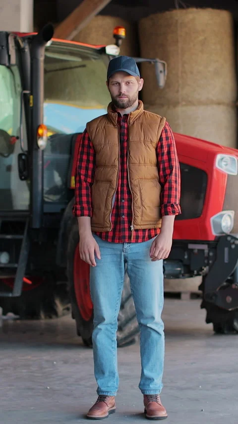 Vertical video. farmer standing in a shirt and orange vest looking at the camera Stock Footage 344630685