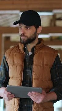 Vertical video. Farmer using tablet computer in modern dairy farm facility co Stock Photos