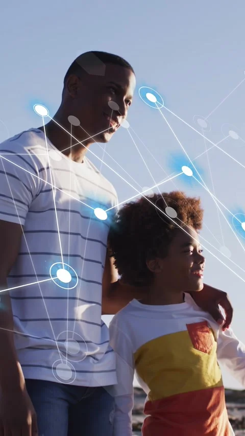Vertical video: Father-son pair walking shore blue node net emerging left 動画素材 333821418