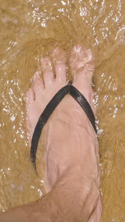 Vertical video. Feet in Flip-Flops Sink Slightly into Wet Sand as Gentle Waves Stock-Footage 280600316
