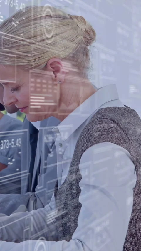 Vertical video: Female analyst leaning writing as data overlay showing and Stockbeeldmateriaal 335513228