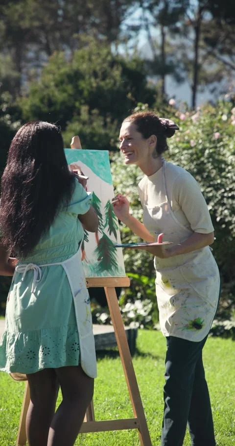 Vertical video: Female art tutor and student painting foliage on easel after Stock Footage 345394985
