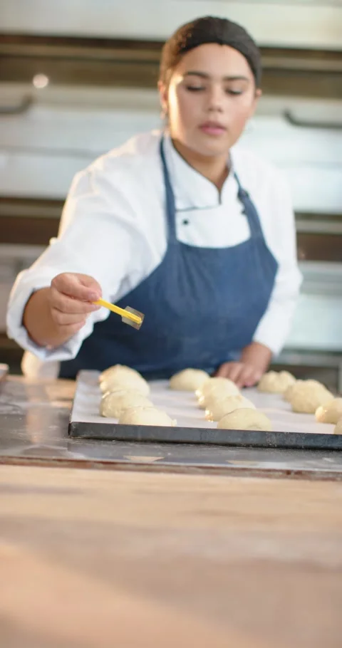 Vertical video: Female baker in chef jacket glazing dough on tray with pastry Stock Footage 345322755