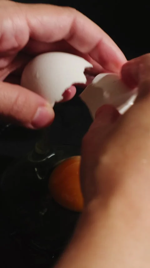 Vertical video. Female hands breaking egg to cook fried eggs in a pan Stock Footage 340335593