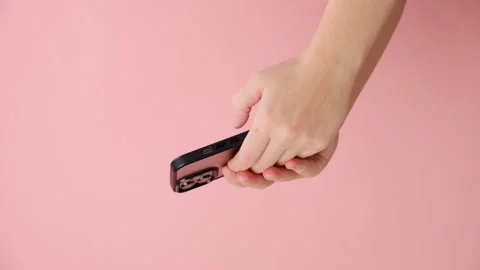Vertical video of female hands using smartphone, posing isolated over pink wall Stock Footage 253500016