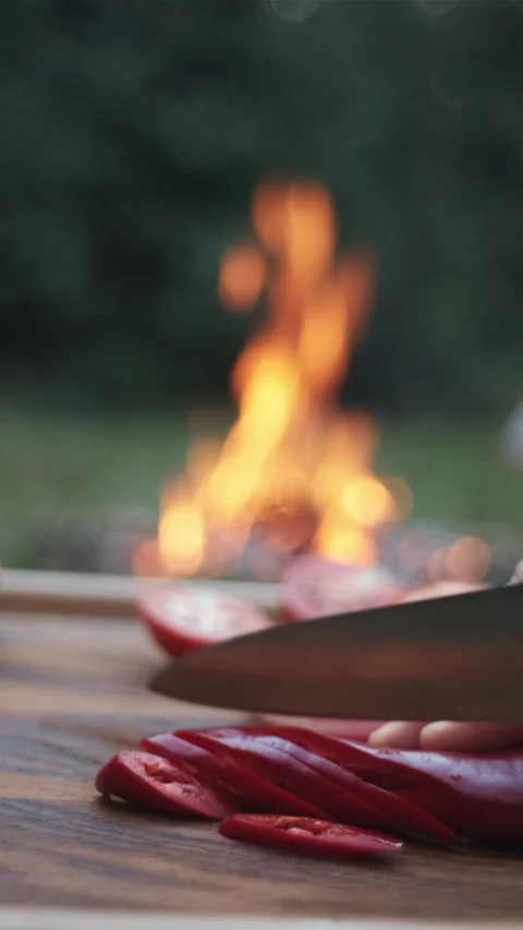 Vertical video of female hands using knife cutting red pepper near bonfire Stock Footage 284927529