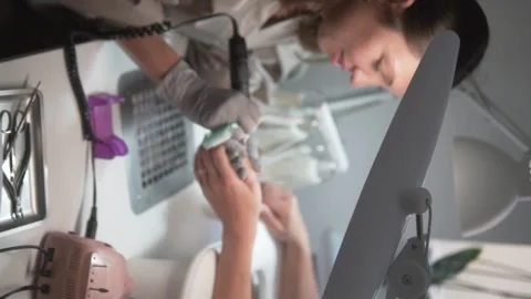 Vertical video, female master doing nail manicure in beauty salon Stock Footage 312339257