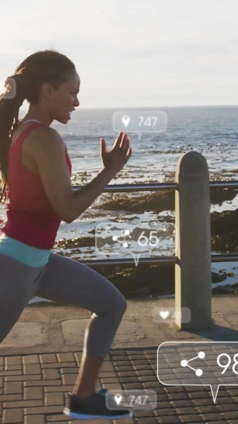 Vertical video: Female runner sprinting seaside, watch sending fitness data, HUD Stock Footage 331721334