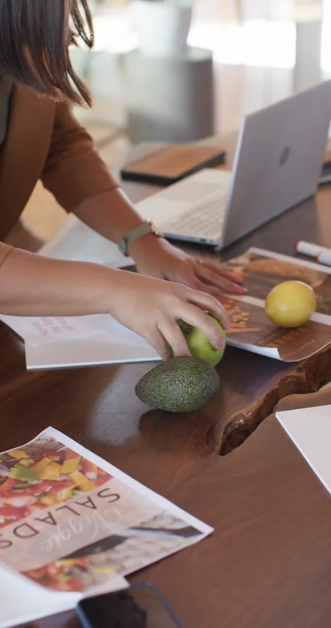 Vertical video: Female team arranging menu with apple on desk then noting layout Stock Footage 335168962