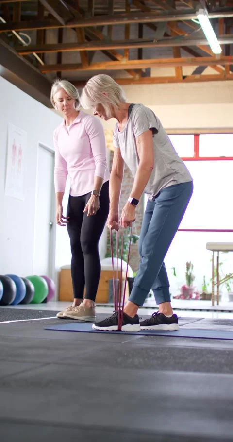 Vertical video: Female trainer guiding while client stepping on band, hinging in Stock Footage 342036191