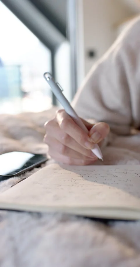 Vertical video: Female writing while pen touching paper, taking notes in bed Stock Footage 348156923